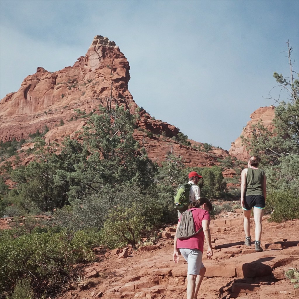 Three adults hiking in dry land with red rocks