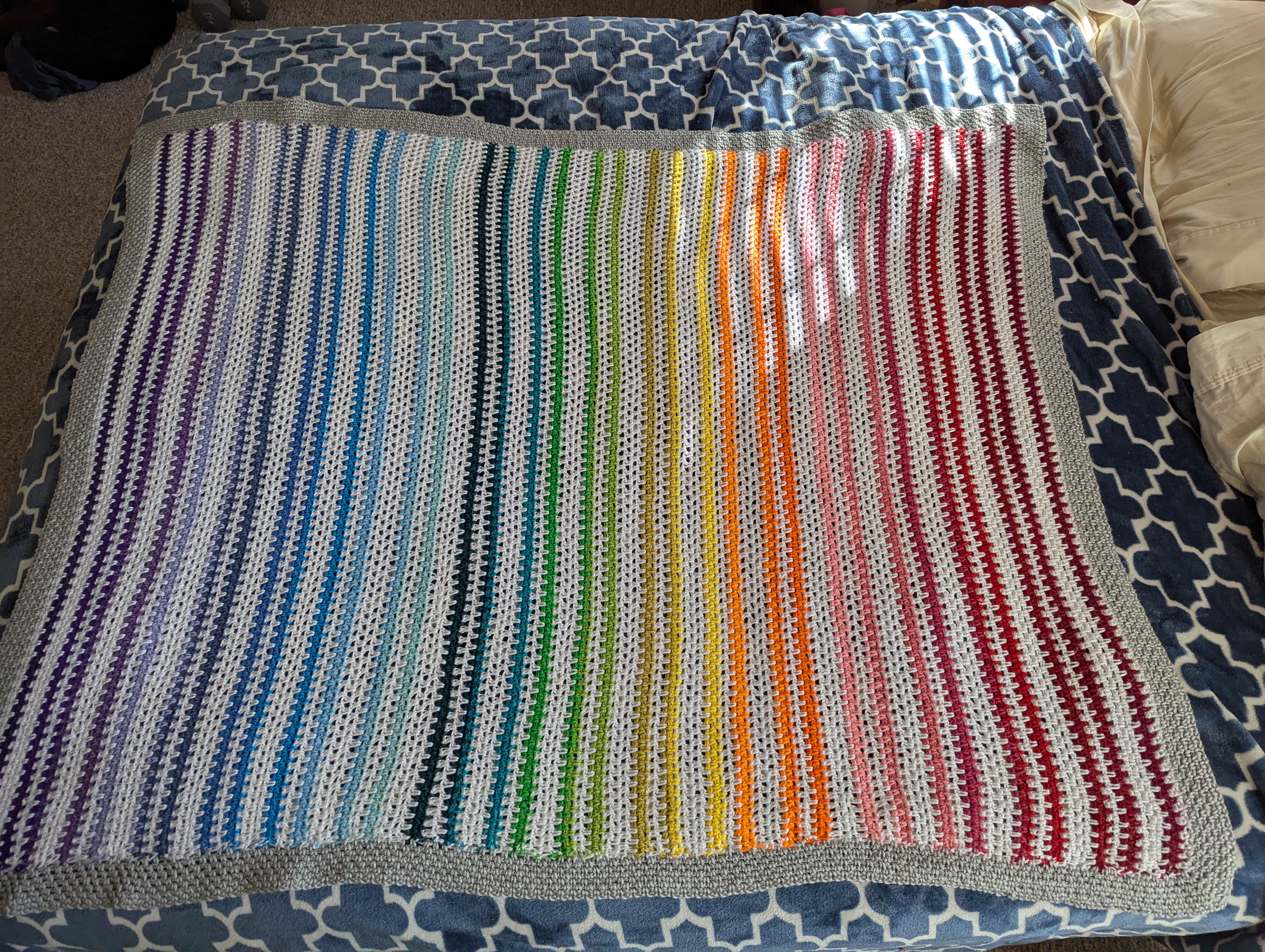 A bright white and rainbow striped crochet blanket
